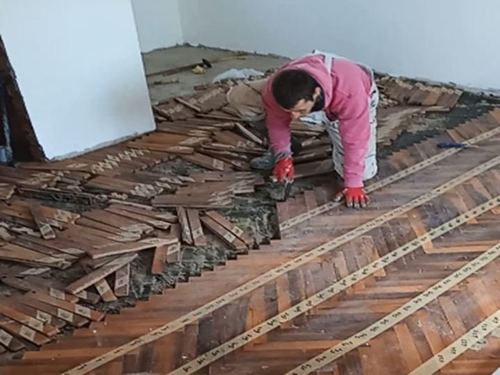 Majstor skida stari parket u stanu — renoviranje u toku
